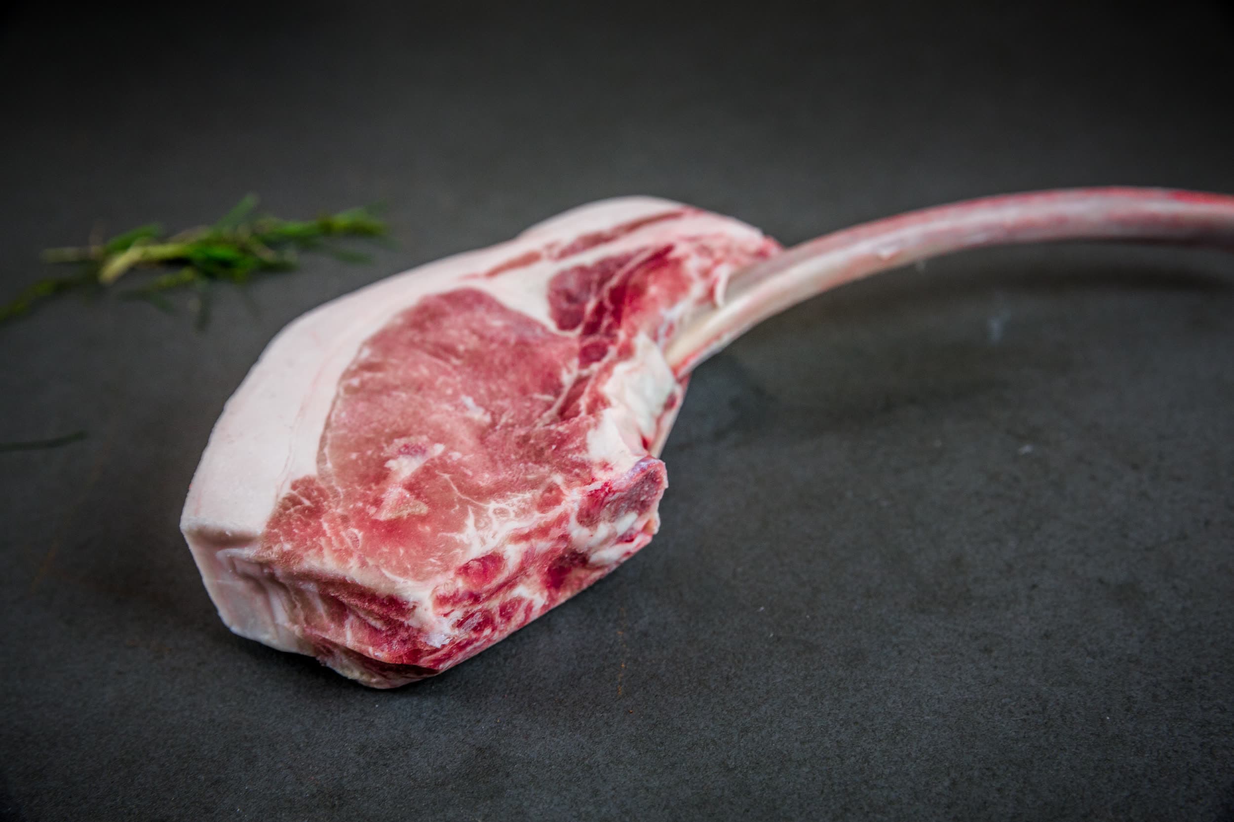 Trockengereiftes Tomahawk-Steak vor dunklem Hintergrund